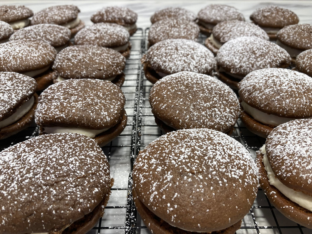 Rows of freshly baked chocolate whoopie pies dusted with powdered sugar